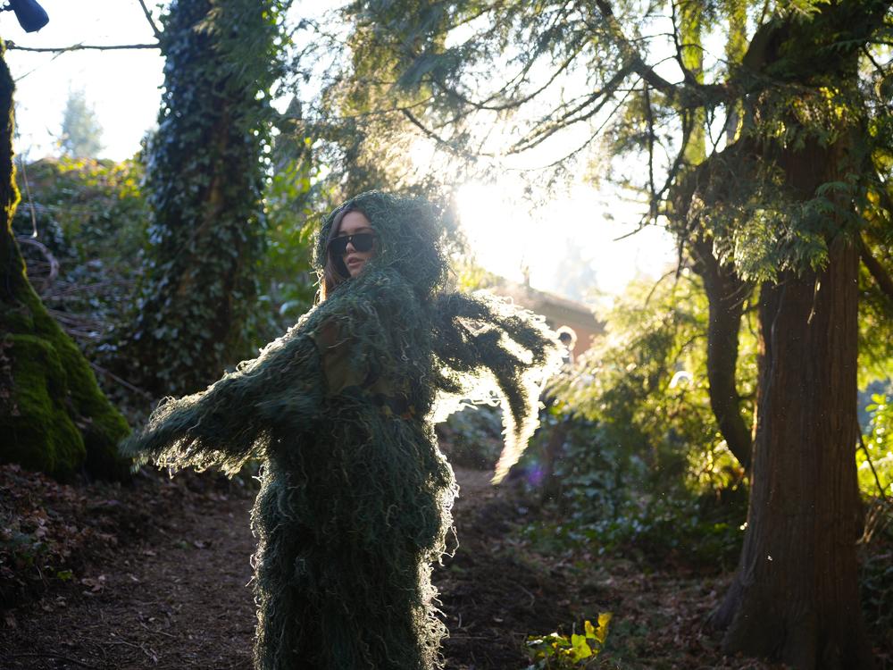 Lewis & Clark student Mira Schwaller donned a moss costume to blend into the campus woods as part of Moss Appreciation Week, 2024.<br>