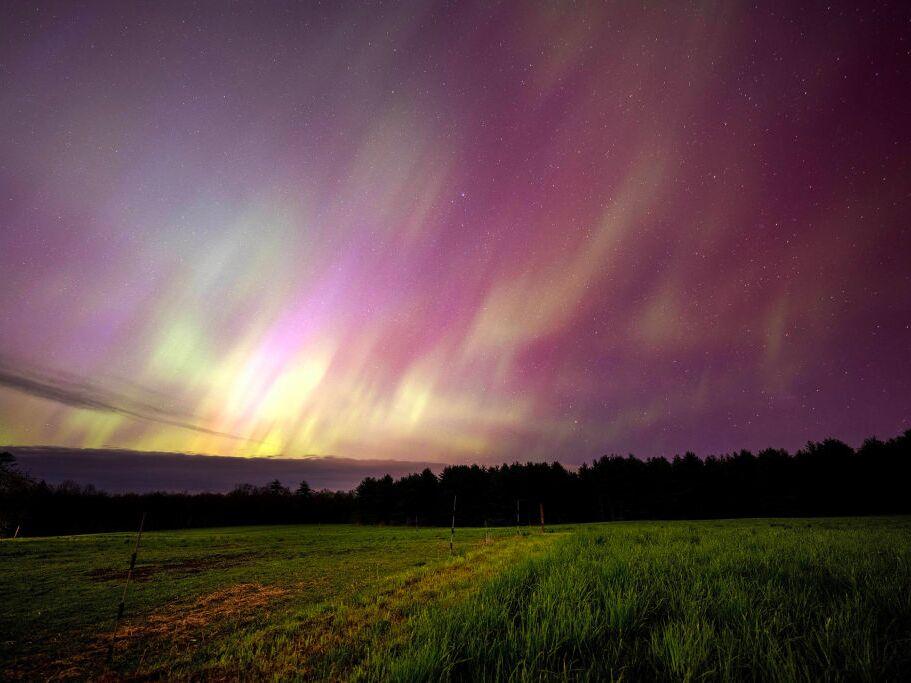 The aurora borealis, commonly called the northern lights, illuminate the sky over a horse pasture in Mercer, Maine on May 10, 2024.