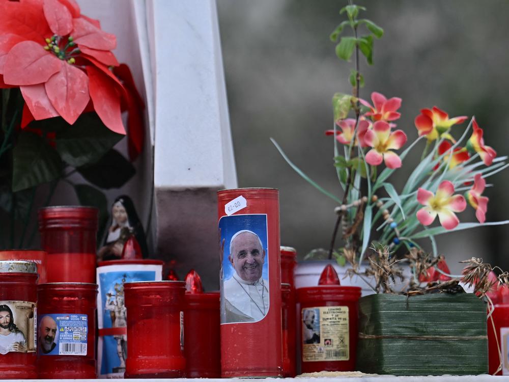 A candle with a picture of Pope Francis is set at the bottom of a statue of Pope John Paul II at the Gemelli Hospital in Rome on Saturday, where Pope Francis is hospitalized for tests and treatment.