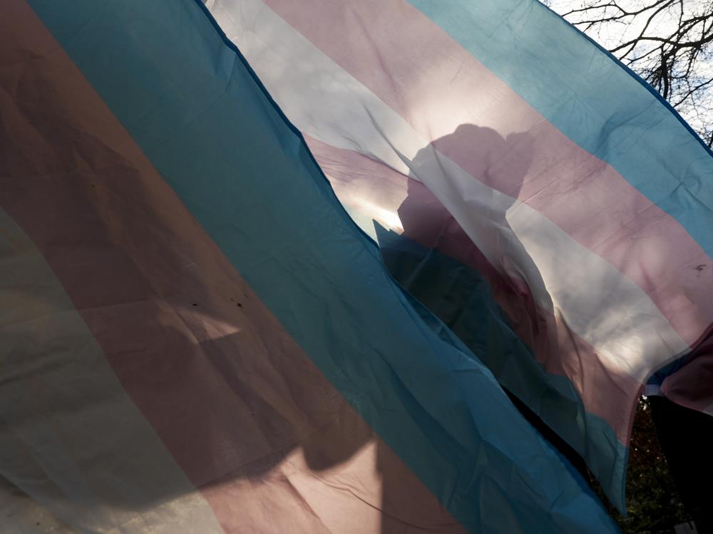 A protester is silhouetted against a trans pride flag during a pro-transgender rights protest outside of Seattle Children's Hospital, in Seattle, on Feb. 9.