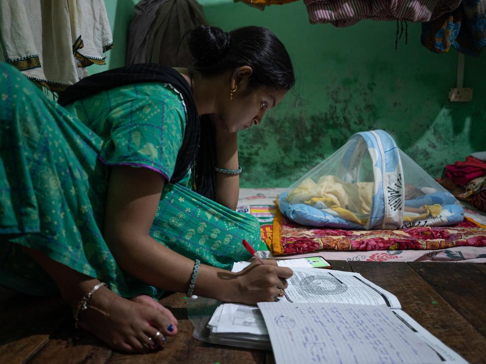 Arti Kumari, 24, makes notes while listening to online videos to prepare for upcoming government examinations while taking care of her newborn at her village home in Bihar. Unable to join in-person classes as she tries to balance household work and child care, she has turned to online videos to prepare for the exam — her only hope of having a career.