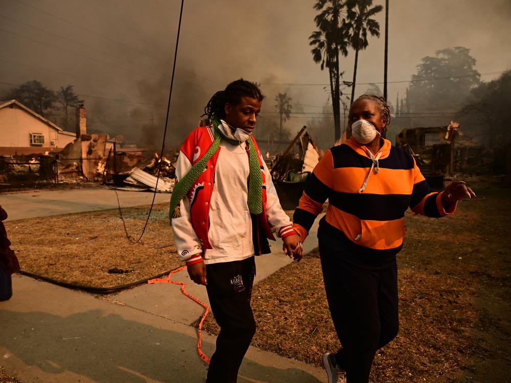 Residents walk past homes burnt by the Eaton Fire in Altadena on Jan. 8.