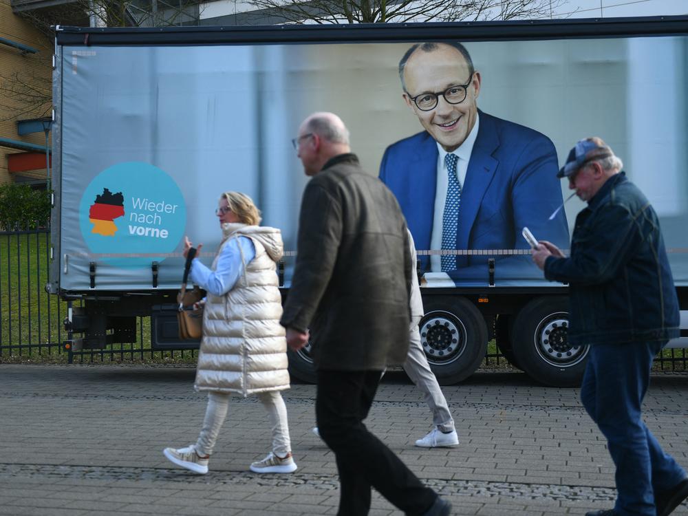 People walk past a truck with an election campaign poster featuring Friedrich Merz, leader of conservative Christian Democratic Union (CDU), in Oberhausen, Germany, on Feb. 21.