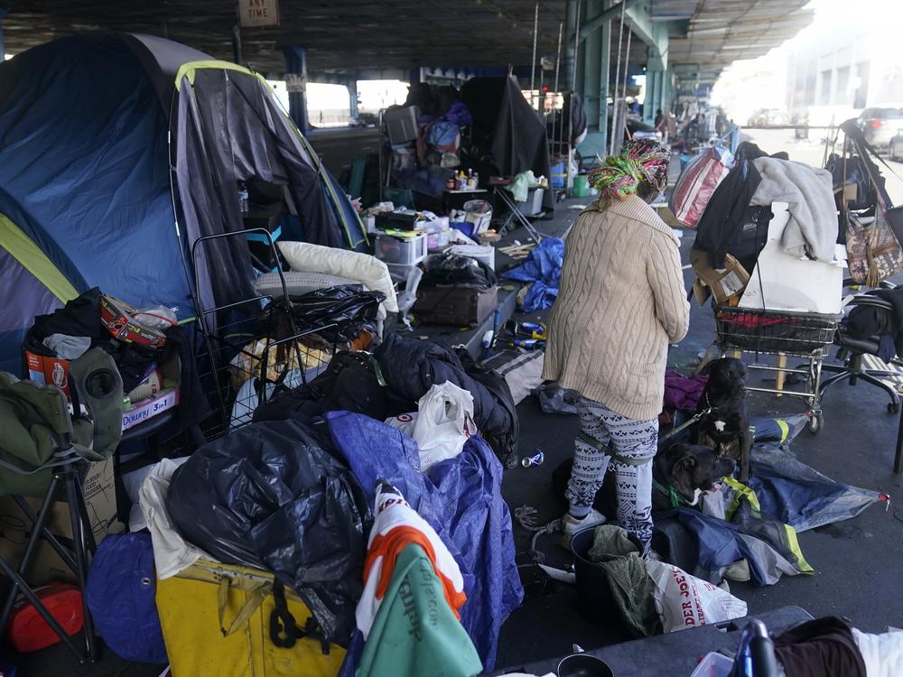 A woman gathers possessions to take before a homeless encampment was cleaned up in San Francisco in 2023. The Trump administration plans to cut most federal staff in the HUD office that funds homelessness programs at a time when the number of people in the U.S. without housing is at a record high.