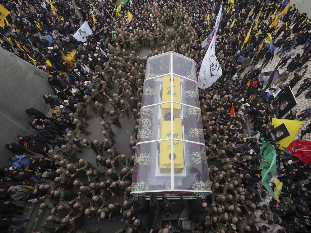 A trailer carrying the coffins containing the bodies of Hezbollah's former leader Hassan Nasrallah and his cousin and successor Hashem Safieddine drives through the crowd during a funeral procession at the Sports City Stadium in Beirut, Lebanon, Sunday, Feb. 23, 2025. (