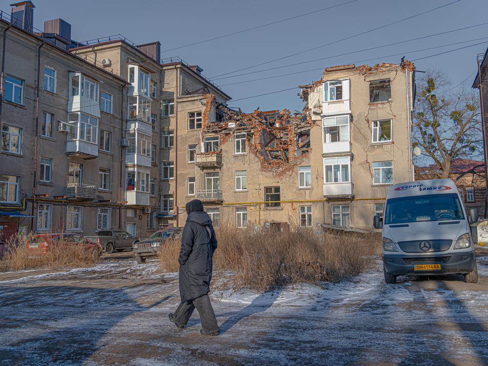 A woman walks in front of a damaged residential building in Sumy on Feb. 9.