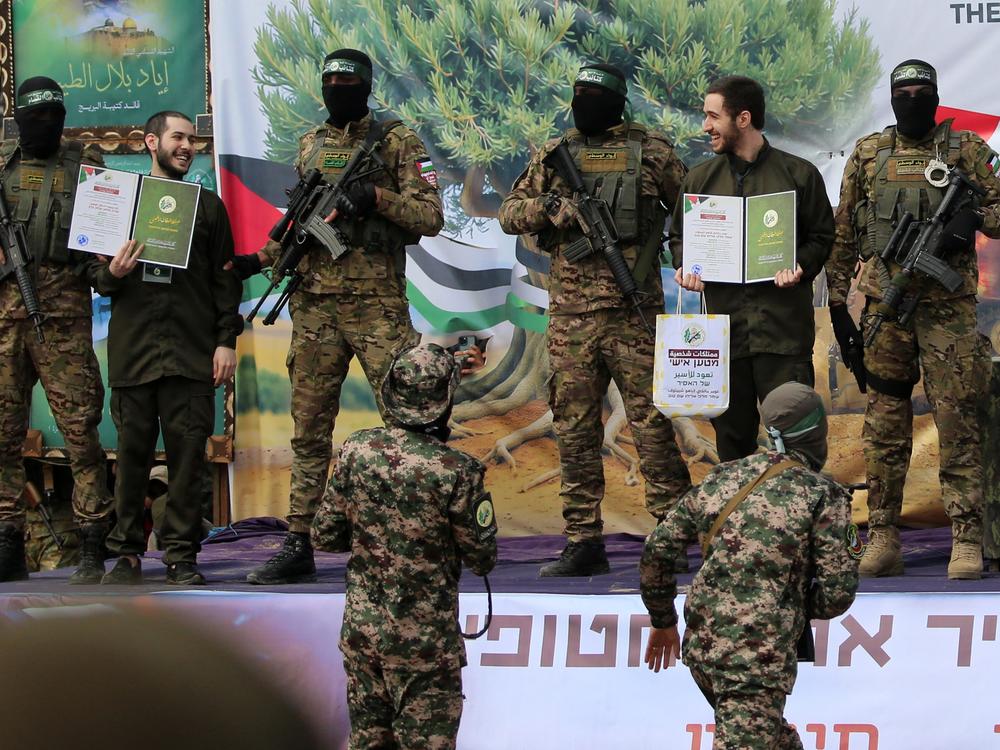Israeli hostage Eliya Cohen (L) and Omer Shem Tov smile to each other as they stand on stage accompanied by Hamas fighters in Nuseirat in the central Gaza Strip, after their release as part of the seventh hostage-prisoner exchange on February 22, 2025.