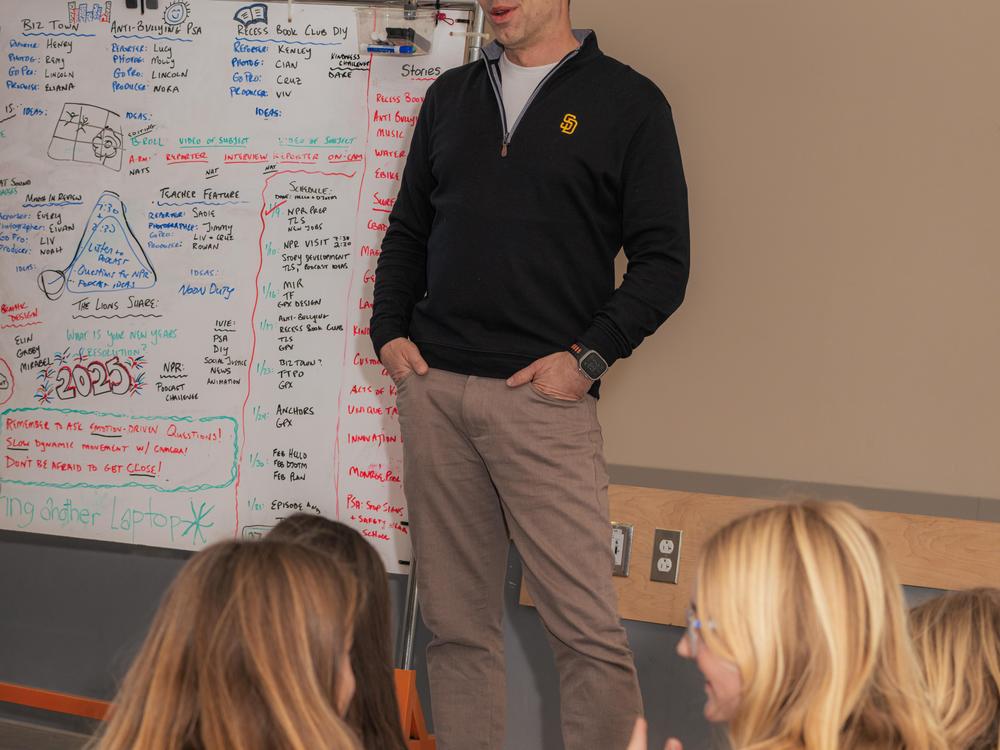 Andrew Luria, parent, MagTV director and evening news anchor, talks to the 10- and 11-year-old journalists at the start of their morning meeting.