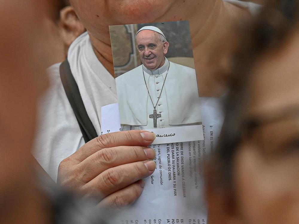 A worshipper carries a picture of Pope Francis as large crowds gather for Mass, led by Archbishop Jorge García Cuerva of Buenos Aires, to pray for the health of Pope Francis, in Buenos Aires, Argentina, Monday.
