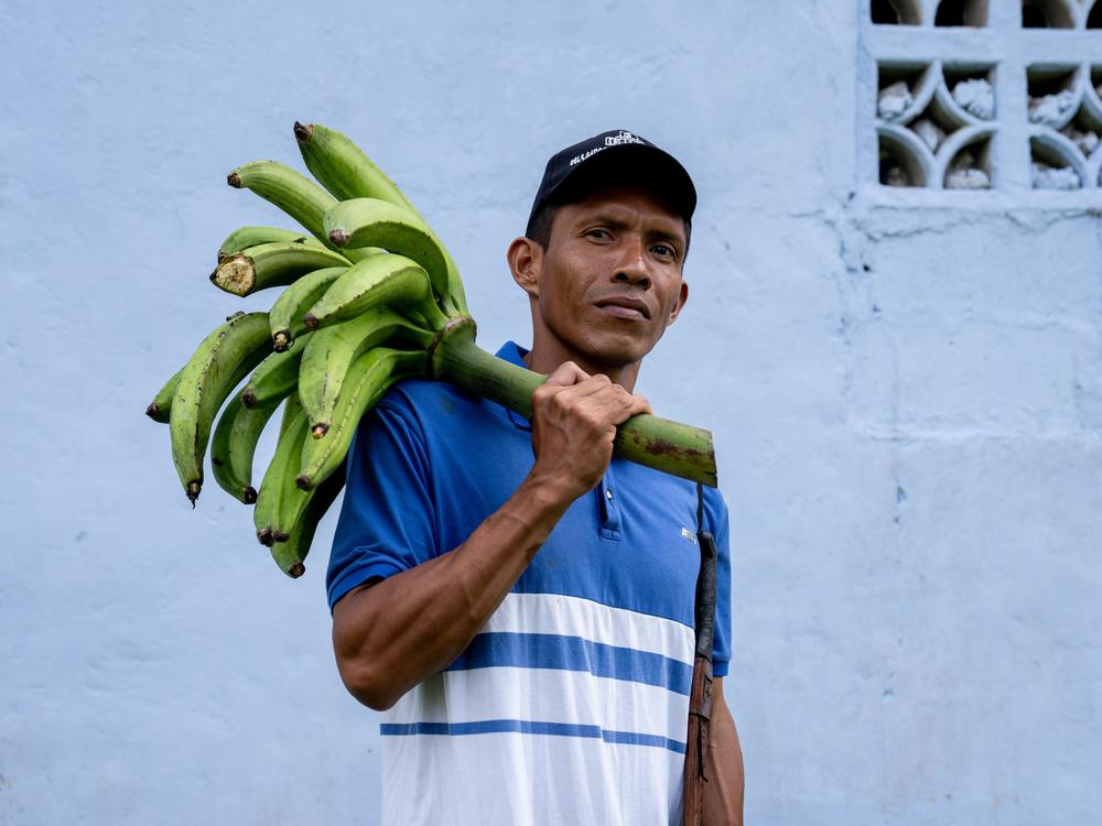 Olegario Cedeño, 38, holds plantains outside a church in Limón de Chagres, Panama. Cedeño is among several dozen community members who are rallying against the planned construction of the Río Indio dam project.