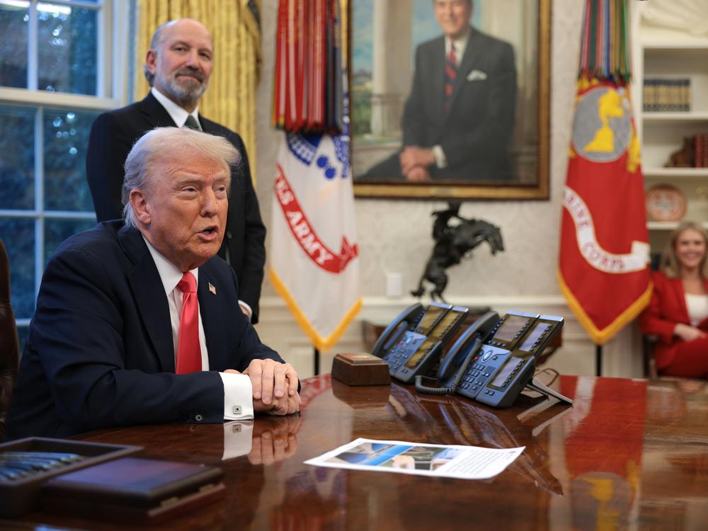 President Trump speaks to reporters as Commerce Secretary Howard Lutnick looks on in the Oval Office on Feb. 25, 2025.