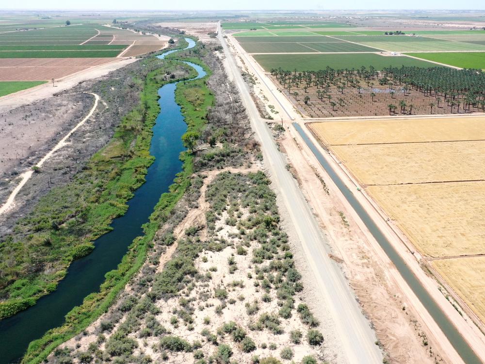 An aerial view shows the long-depleted Colorado River (L) as it flows between California (R) and Arizona, and an irrigation ditch (R) carrying river water toward Quechan tribal land on May 26, 2023 near Winterhaven, California.