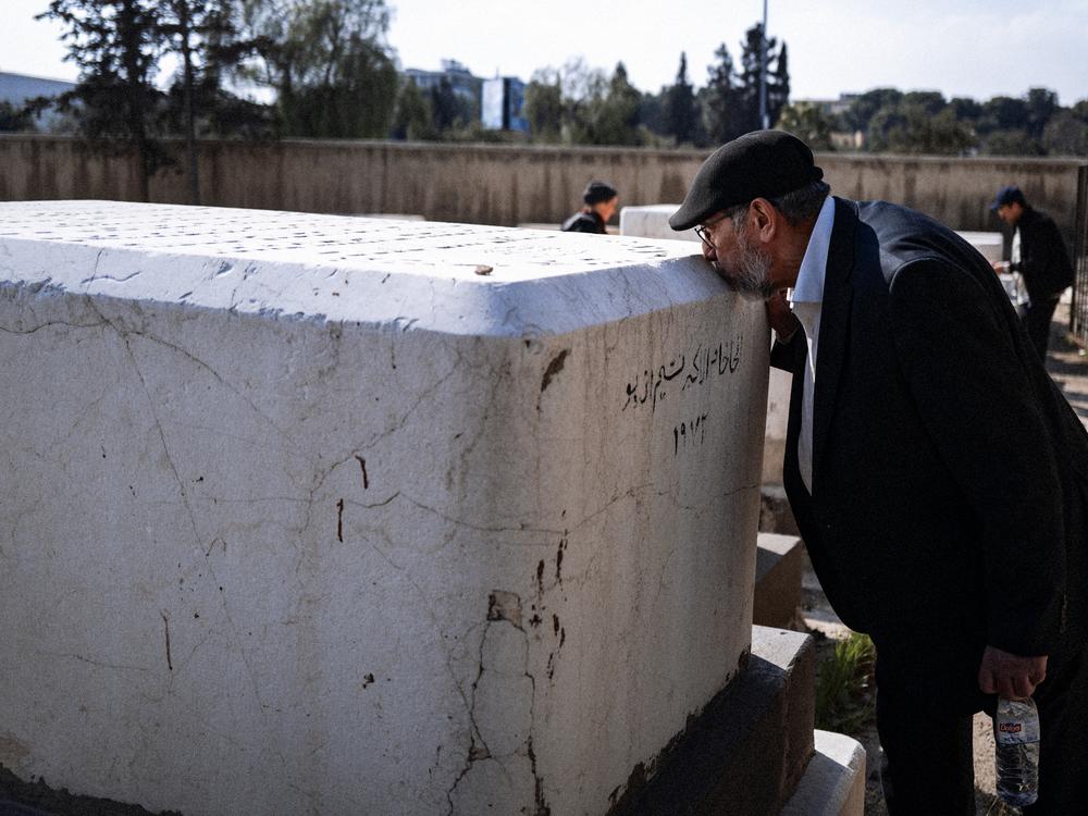 Rabbi Yusuf Hamra kisses a tombstone belonging to his teacher in the historic Jewish cemetery of Damascus.