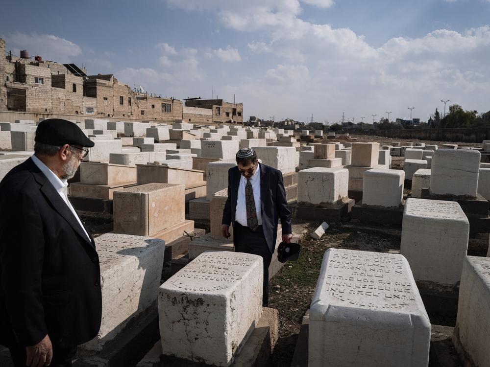 Rabbi Asher Lopatin and Rabbi Yusuf Hamra walk among tombstones engraved in Hebrew in the historic Jewish cemetery of Damascus.
