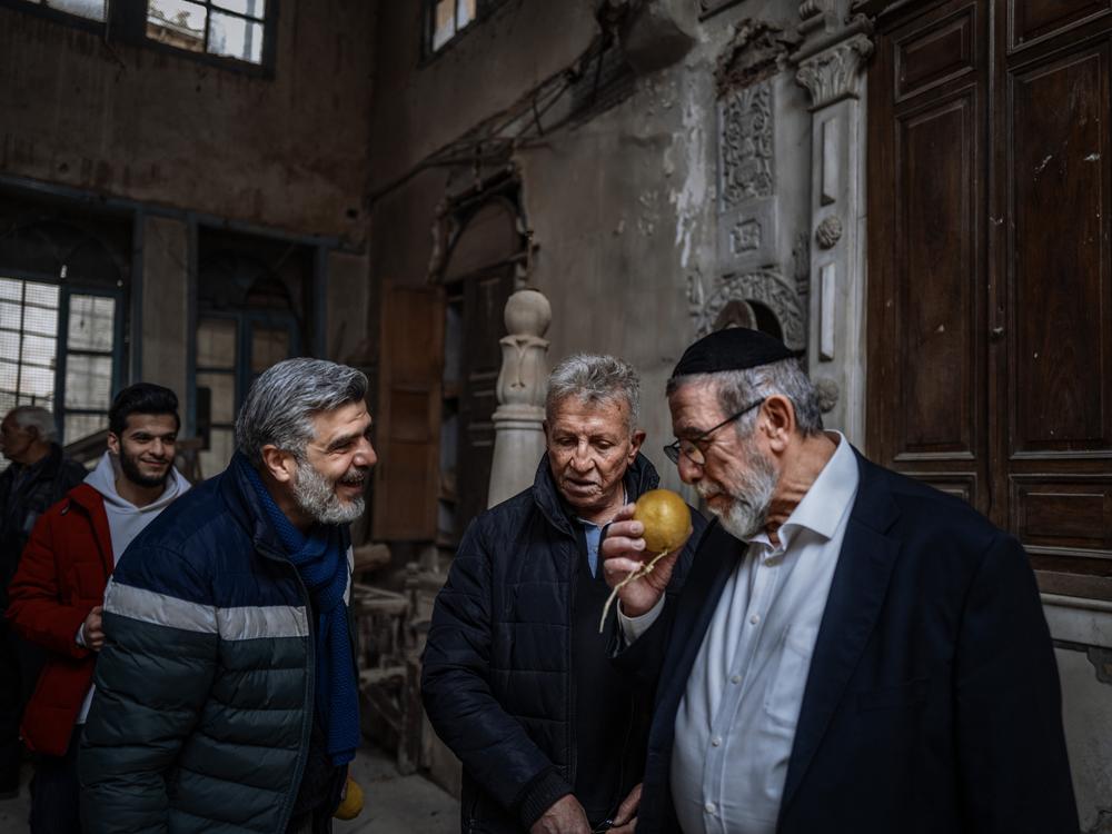 Rabbi Yusuf Hamra smells a citrus fruit with former neighbors in Old Damascus.