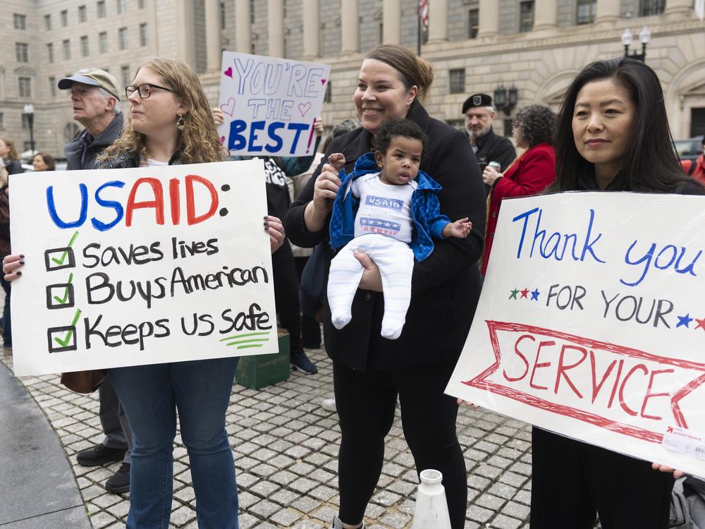 United States Agency for International Development (USAID) supporters hold banners as USAID workers retrieve their personal belongings from the USAID's headquarters in Washington, Thursday, Feb. 27, 2025.