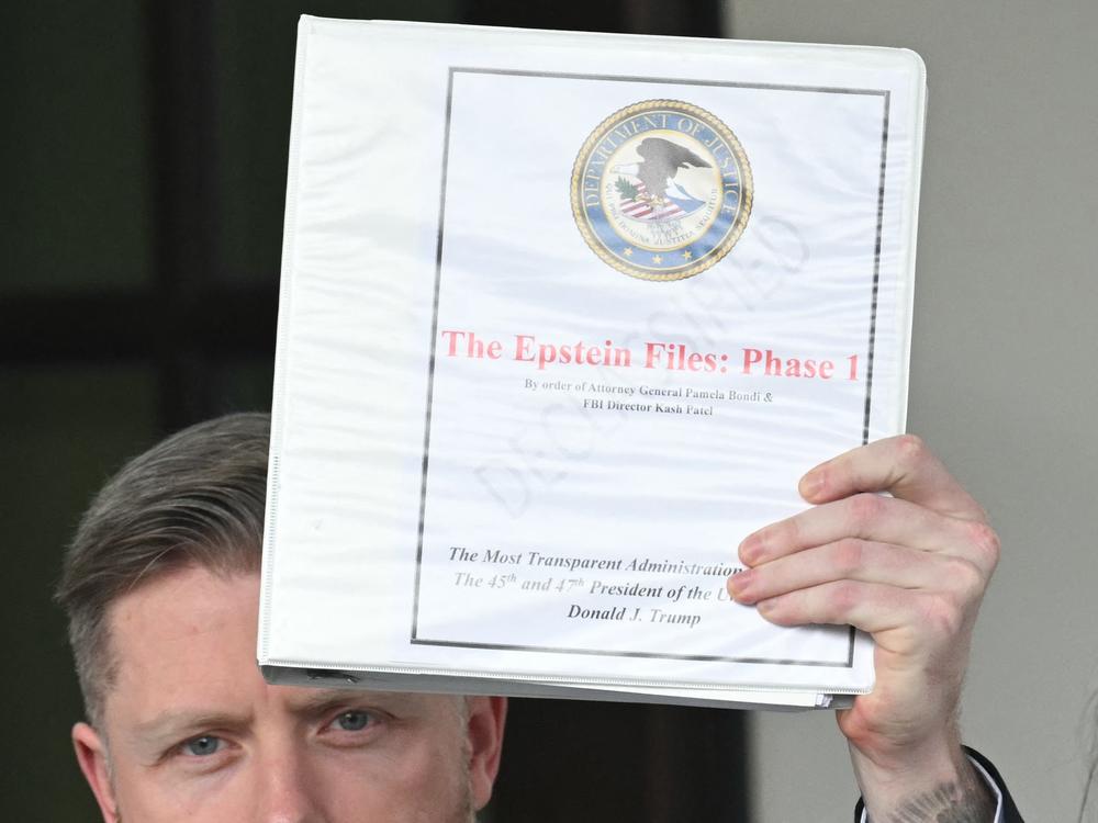 Political commentator Rogan O'Handley, aka DC Draino, holds up the binder titled 