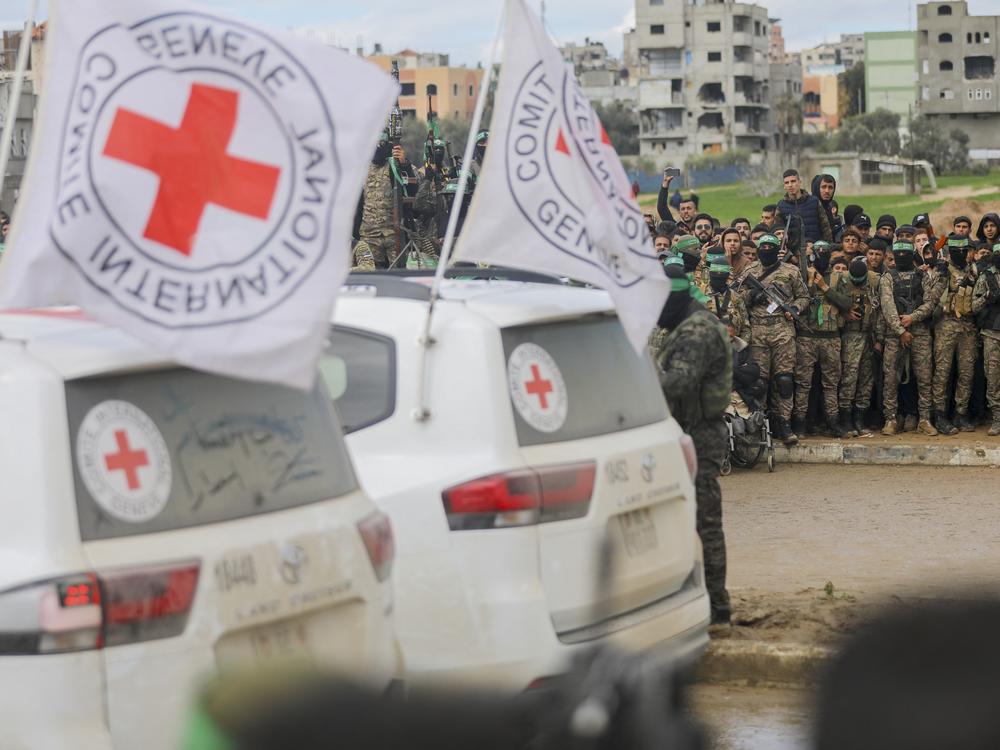 Hamas fighters stand guard as an International Red Cross vehicle arrives at the site of the handing over of two Israeli hostages in Rafah in the southern Gaza Strip, as part of the seventh hostage-prisoner release on February 22, 2025.