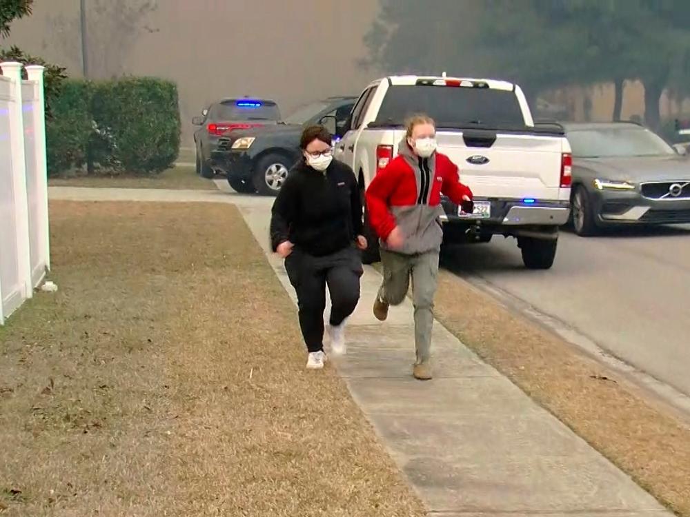 People move from an area where crews work to contain a fire in the Carolina Forest area west of the coastal resort city of Myrtle Beach, S.C., Sunday, March 2, 2025, where residents were ordered to evacuate several neighborhoods.