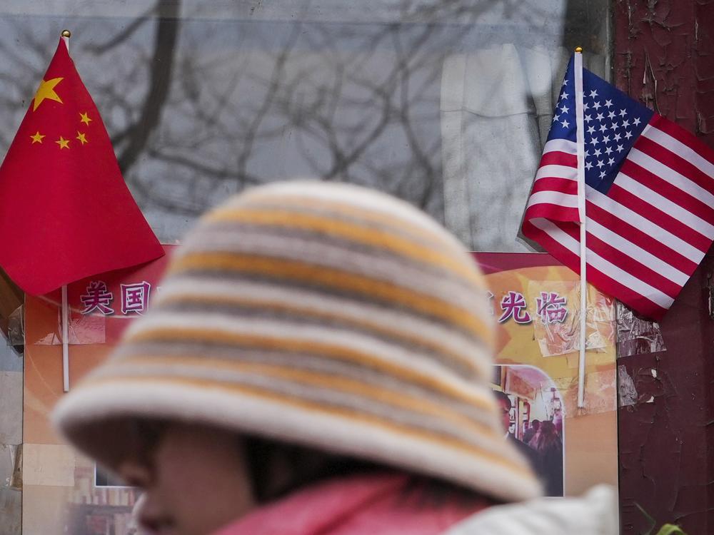 A woman walks by the Chinese and U.S. national flags on display outside a souvenir shop in Beijing on Jan. 31, 2025.