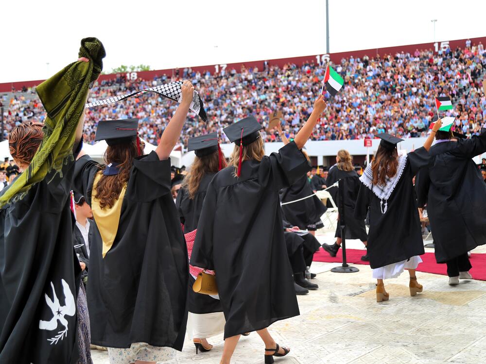 Pro-Palestinian students hold up Palestinian flags during UMass Amherst graduation ceremonies in May 2024. They left the graduation event in protest.