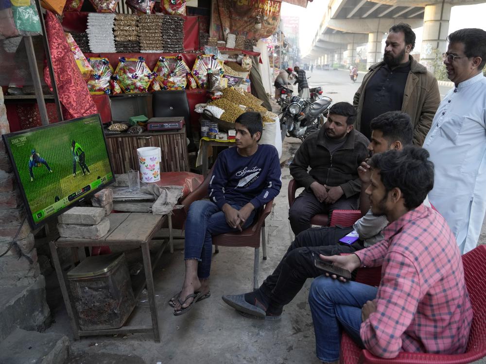 Cricket fans watch the ICC Champions Trophy cricket match between Pakistan and India on a television at a roadside shop in Lahore, Pakistan, Sunday, Feb. 23.