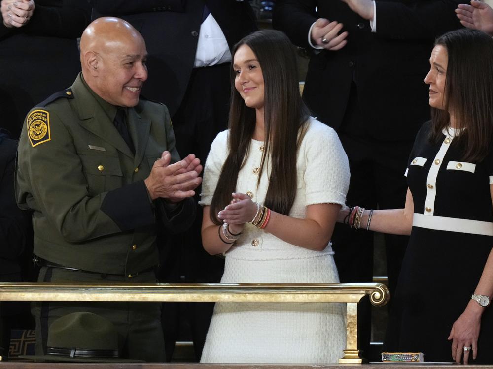 Border patrol agent Roberto Ortiz, from left, looks on as Lauren Phillips and Allyson Phillips, family members of the late Laken Riley, watch as President Trump addresses a joint session of Congress.