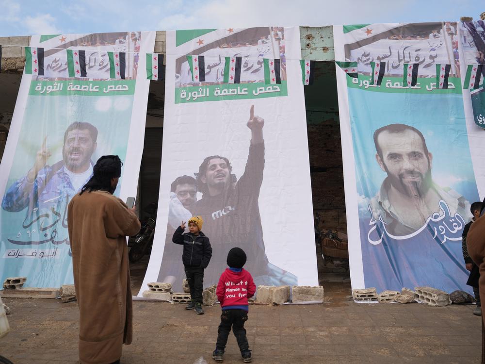 People pose for photos in front of a banner of Abdel Basset al-Sarout in Homs, Syria, on Jan. 31.