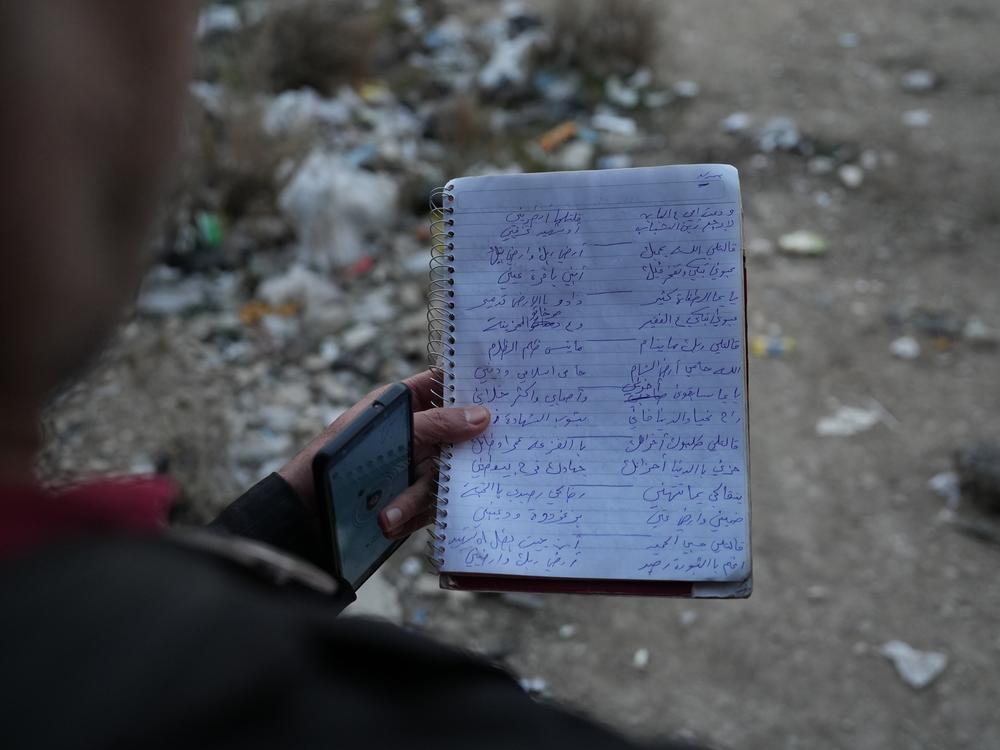 Ayman al-Masri reads from his notebook of lyrics outside the remains of Sarout's family home.