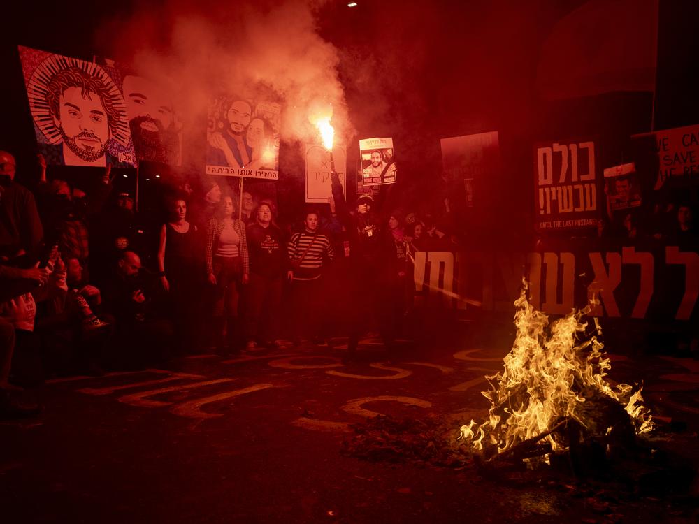 Freed hostage Ilana Gritzewsky holds a smoke torch as protesters set a fire during a demonstration calling for the release of all hostages held by Hamas in Gaza on Saturday in Tel Aviv. Israel's domestic security agency says it now had Hamas' battle plans and other warnings for the Oct. 7, 2023 attacks but failed to take them seriously.