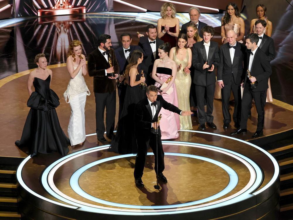 Cast and crew led by director Sean Baker accept the best picture award for <em>Anora </em>at the Oscars.