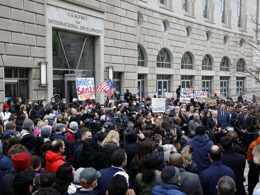 The Trump administration's plans for mass firings are sparking protests and challenges in court. Here, supporters of the U.S. Agency for International Development join Sen. Chris Van Hollen, D-Md., and Rep. Gerry Connolly, D-Va., outside USAID's headquarters in Washington, D.C., on Feb. 3 after Elon Musk, who oversees the Department of Government Efficiency, said he and President Trump would close the foreign assistance agency.