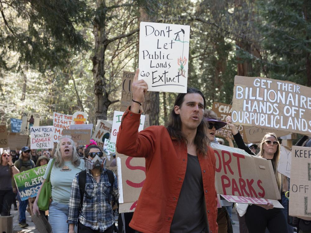 Alex Wild (center), a former National Park Service ranger who was fired on Feb. 14, holds a sign during a protest against widespread layoffs at Yosemite National Park in California on March 1. The National Parks Conservation Association estimates that 1,000 National Park Service employees who were on one-year probationary periods were laid off. About 3,400 employees of the U.S. Forest Service were among the cuts too, according to multiple media reports.