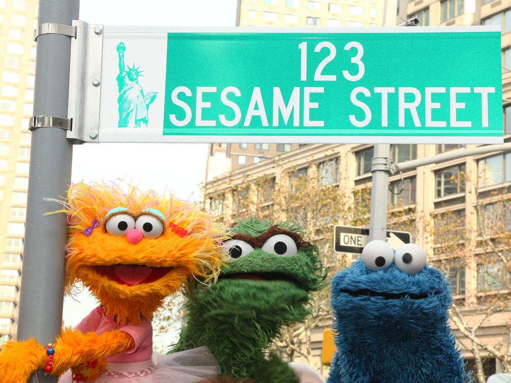 <em>Sesame Street</em> characters pose under a 