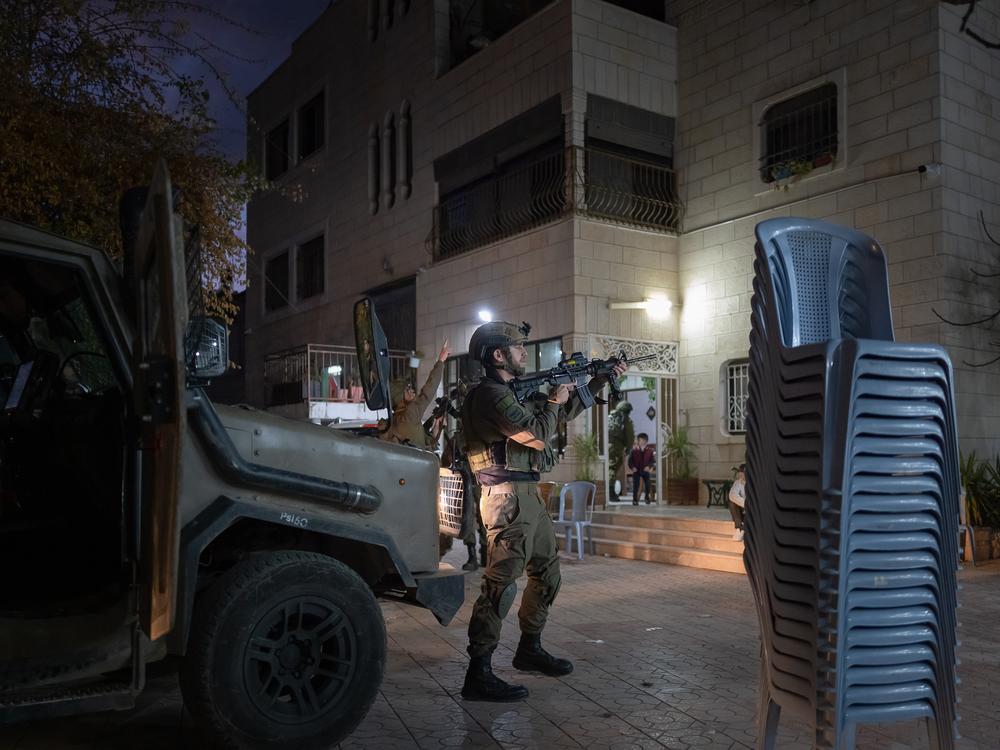 Israeli security forces, with their rifles raised and pointing forward, raid the celebration of Ashraf Zughayer's return home from prison, in East Jerusalem, on Jan. 25.