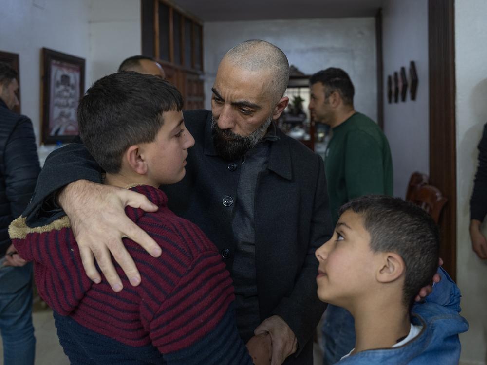 Ashraf Zughayer comforts his nephews after the Israeli army arrested their father and other family members.
