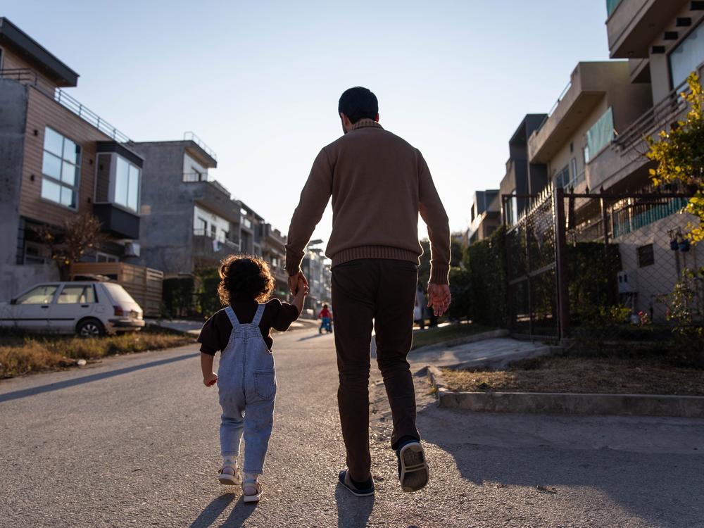 A former employee of Afghanistan's Defense Ministry walks in his neighborhood with his youngest daughter on Jan. 21, in Islamabad, Pakistan.