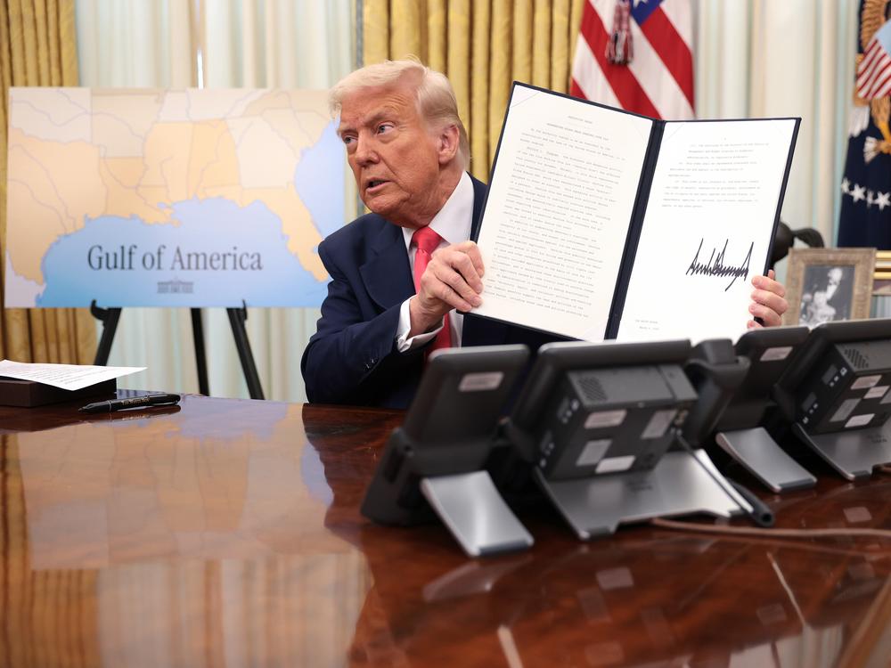 President Trump holds up an executive order after signing it in the Oval Office on March 6, 2025.