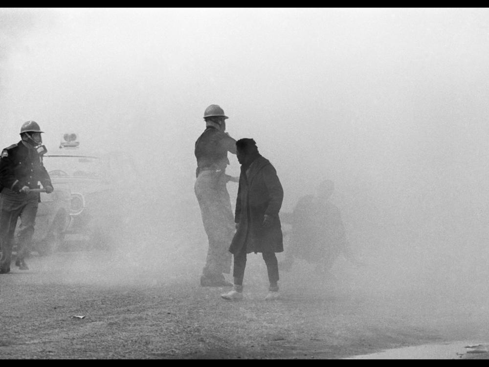 Tear gas overwhelms the scene as marchers continue to flee or fall to the troopers' blows.<br>