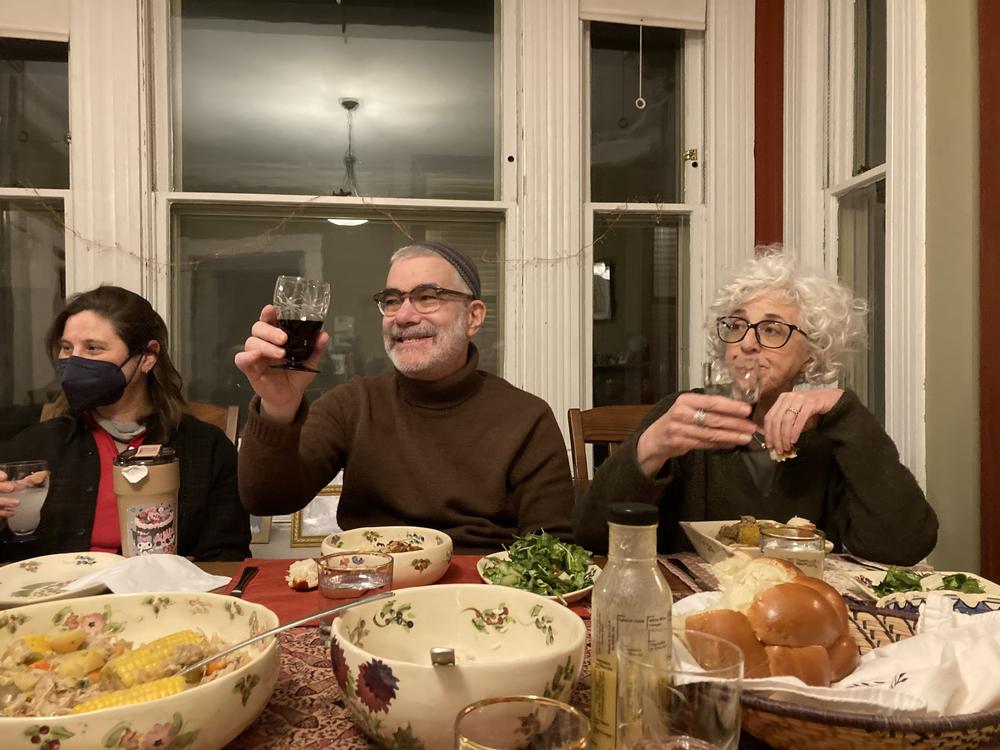 Rabbi Brant Rosen (center) raises a glass of wine at a Friday night Shabbat dinner.