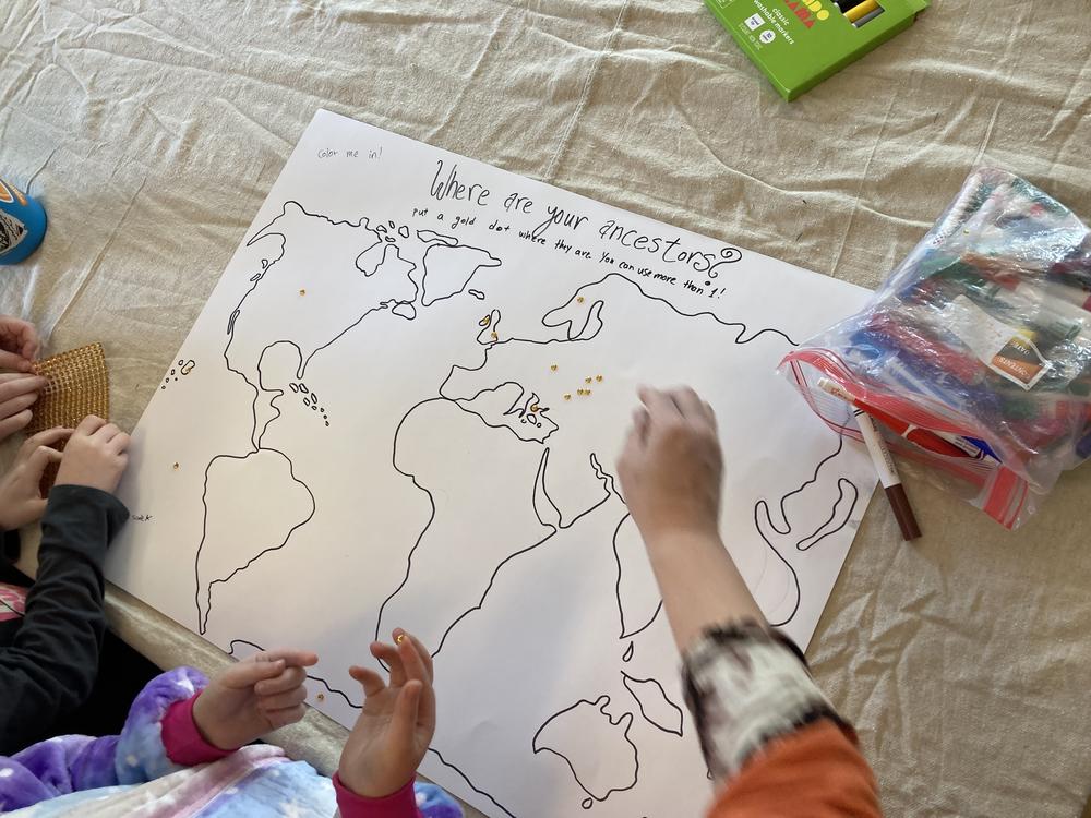 Children place stickers on a map showing where their ancestors are from at Tzedek Chicago's Sunday family program.