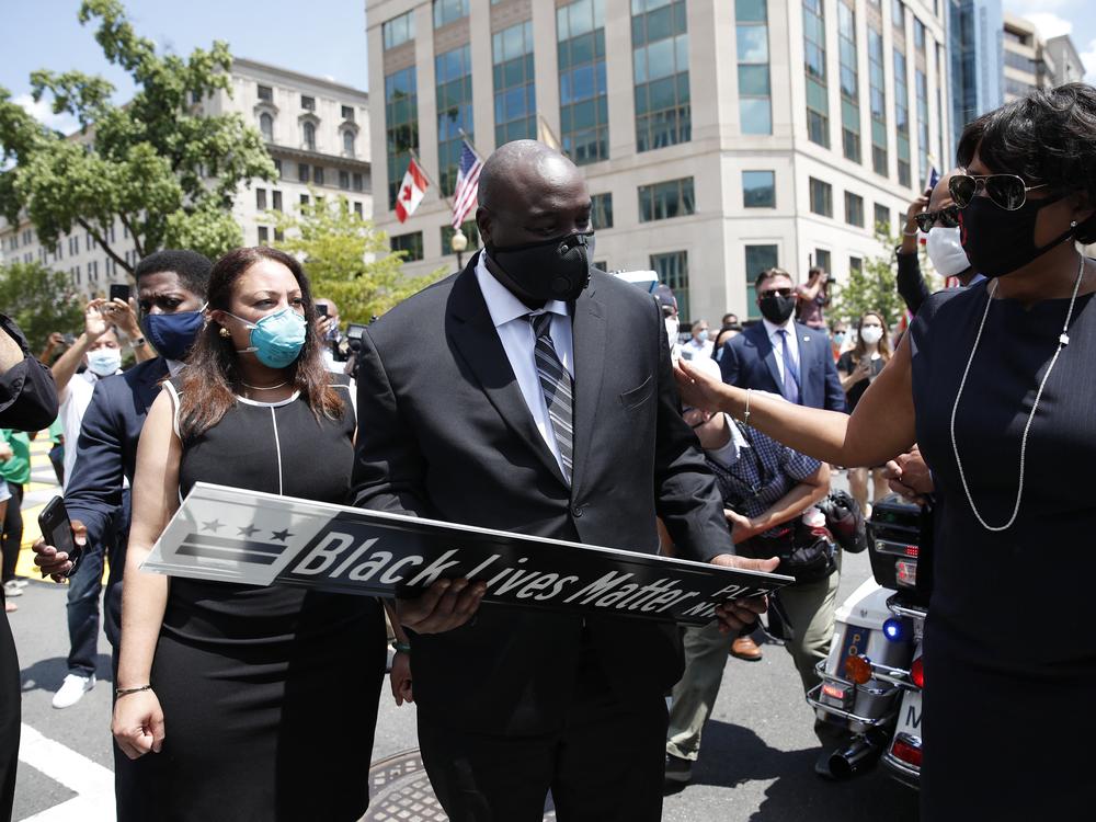 District of Columbia Mayor Muriel Bowser (R) presents a Black Lives Matter Plaza street sign to a representative of the family as the hearse with the flag-draped casket of U.S. congressman and civil rights icon John Lewis drives on 16th Street, renamed Black Lives Matter Plaza, near the White House in Washington, DC July 27, 2020.