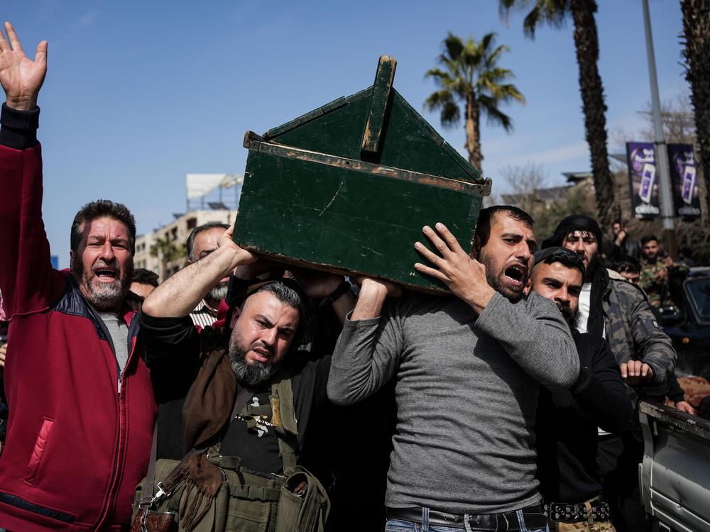 Syrian fighters and civilians carry the coffin of a member of the Syrian security forces during his funeral in Hama province on March 9.