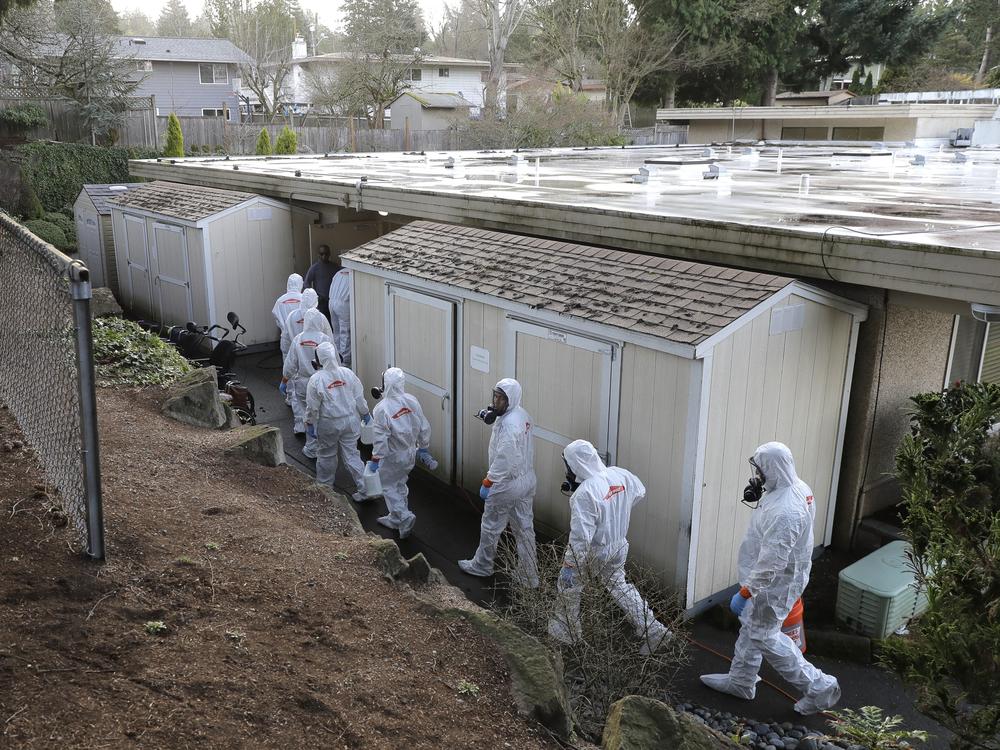 Workers from a Servpro disaster recovery team wearing protective suits and respirators enter the Life Care Center in Kirkland, Wash., to begin cleaning and disinfecting the facility on March 11, 2020.