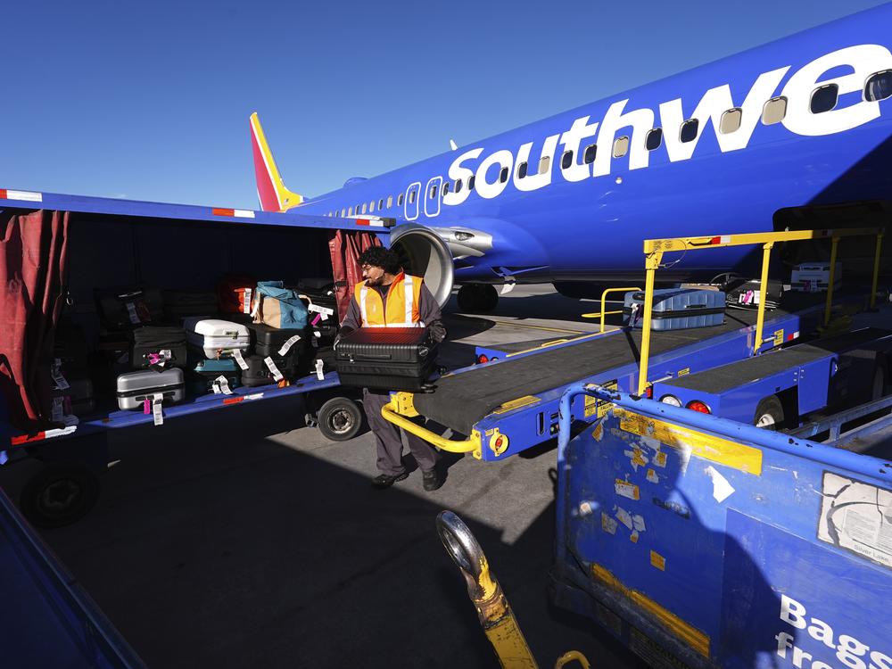 A Southwest Airlines plane is unloaded at Denver International Airport on Thursday, Feb. 27. The airline announced that it would begin charging some passengers to check bags.