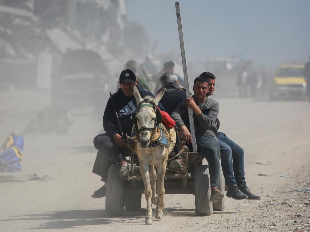 Palestinians ride in the back of a donkey-drawn cart past destroyed buildings west of Jabalia city in the northern Gaza Strip on Tuesday. Israeli officials say they're working on a plan to create a migration authority to help relocate the vast majority of Gaza's two million people.
