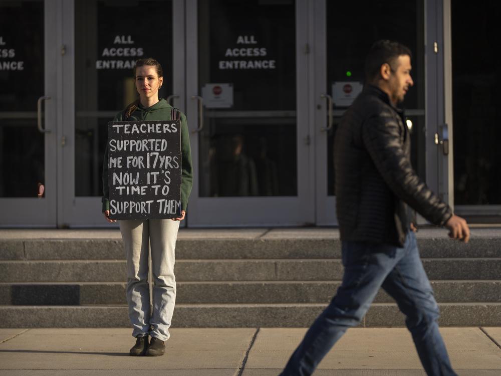 Chloe Kienzle of Arlington, Va., holds a sign as she stands outside the U.S. Department of Education, in Washington, D.C., on Wednesday – the day after the Trump administration announced widespread job cuts at the agency.