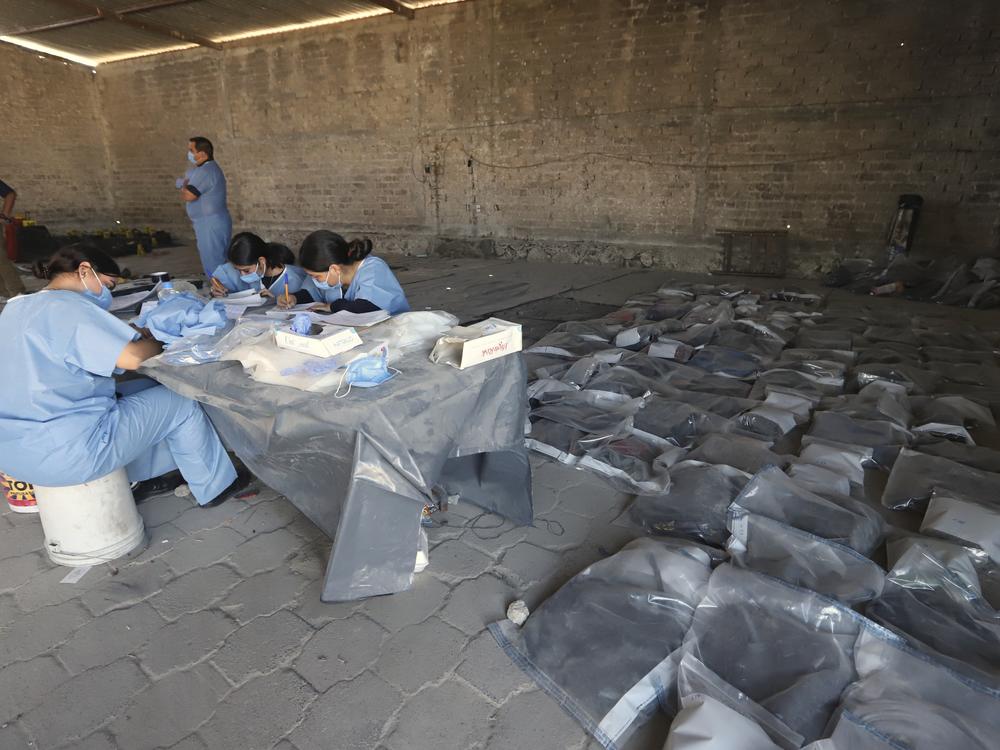 This photo released by the Jalisco State Attorney General's Office shows investigators classifying objects found at the Izaguirre Ranch, where skeletal remains were discovered, in the municipality of Teuchitlan, Mexico on Tuesday.