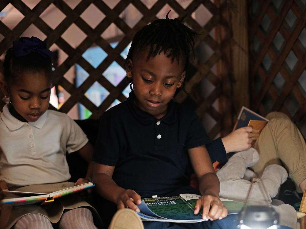 Kindergarteners Khloe Winslow and Alijah Oaks flip through books of their choice in the corner reading nook of their classroom.