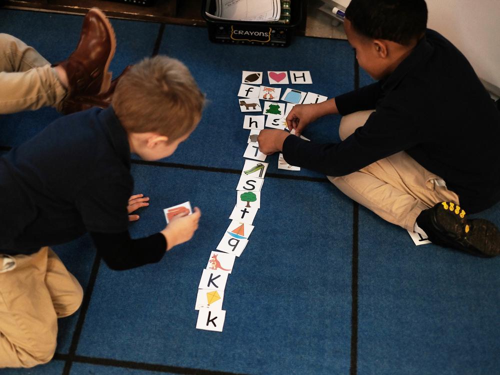 Two students play a card game identifying letter sounds in Vanessa Birdwell's kindergarten classroom at Provencal Elementary.